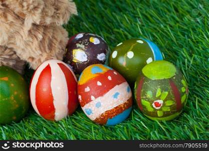 Rabbit, sit on green grass and group of colorful eggs are behind, can use as background for happy easter festival