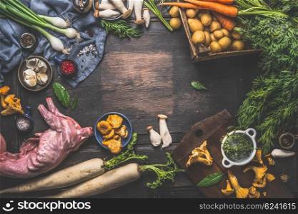 Rabbit stew cooking ingredients: vegetables, mushrooms , herby and spices on dark rustic wooden background, top view, frame