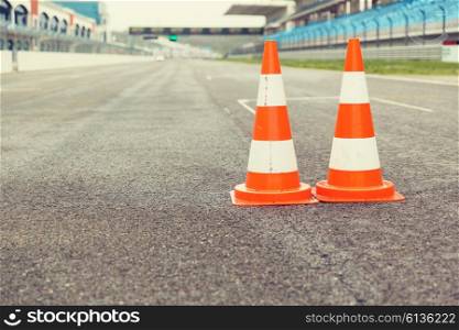 racing, motosports, extreme and motoring concept - traffic cones on speedway of stadium