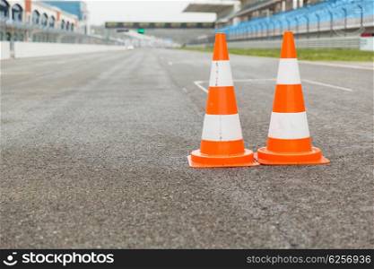 racing, motosports, extreme and motoring concept - traffic cones on speedway of stadium