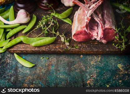Rack of lamb with green pea pods, cooking preparation on rustic background, top view, border