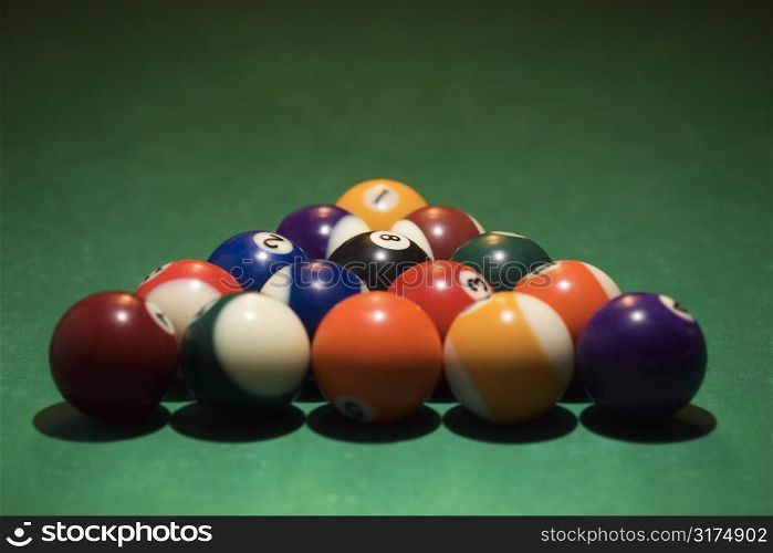 Rack of pool balls on green billiards table.