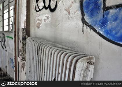 Radiator and stained peeling wall in abandoned building.