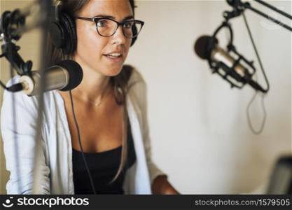 Radio podcast concept - female radio host speaking in microphone in podcasting studio. Podcast Concept - Female Host in Podcasting Studio