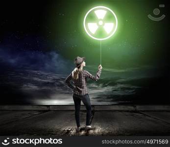 Radioactive hazard. Young woman in casual holding balloon with radioactivity sign