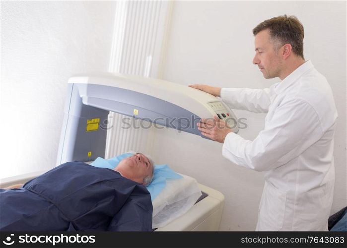 radiologic technician mature male patient lying on scan bed