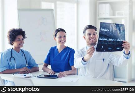 radiology, people and medicine concept - group of happy doctors looking to and discussing x-ray image at hospital