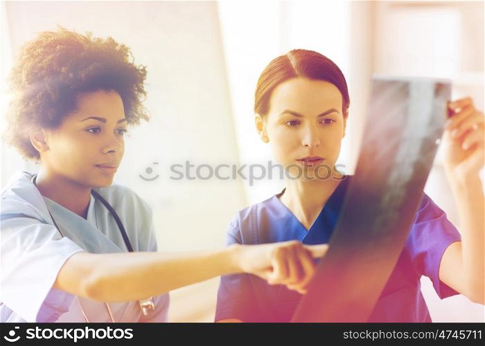radiology, surgery, people and medicine concept - female doctors looking to and discussing x-ray image at hospital