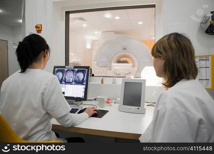 Radiology technicians monitoring MRI scan in progress