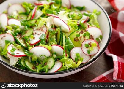 Radish and cucumber salad with fresh green onion in bowl
