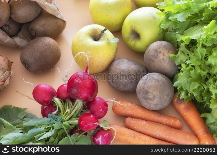 radish bunch and other organic vegetales and fruits on orange background