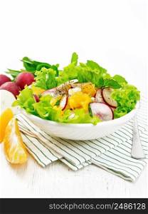 Radish, onion and orange salad with mint, vegetable oil and spices on lettuce in a plate on a towel on wooden board background