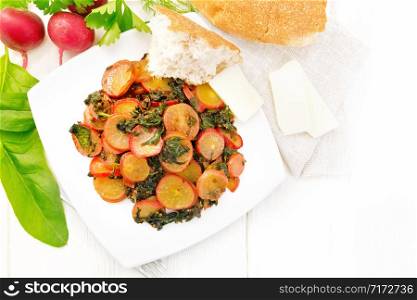 Radish stewed with spinach and spices in a plate, cheese and bread, napkin against wooden board background from above