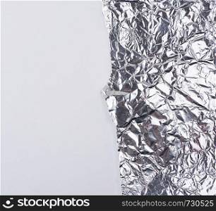 ragged edge of silver foil on a white background, close up, copy spave