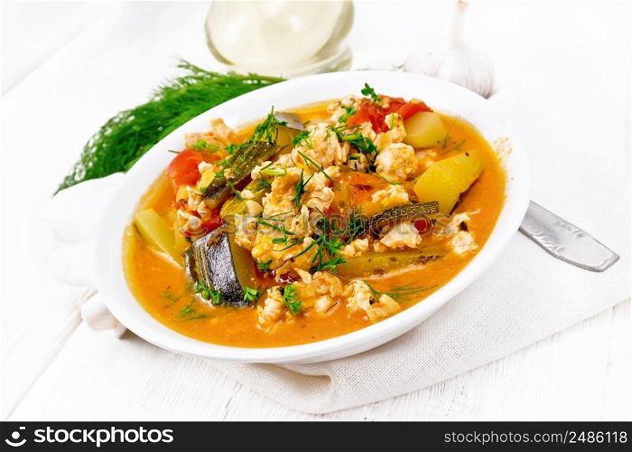 Ragout of zucchini, minced chicken and tomatoes with herbs in a plate on a napkin on wooden board background