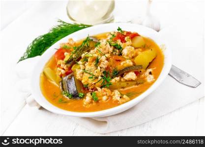 Ragout of zucchini, minced chicken and tomatoes with herbs in a plate on a napkin on wooden board background