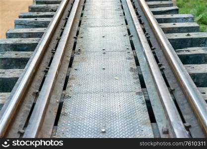 Rail track with wooden sleepers and rusty rails at old railway bridge