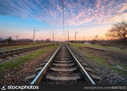 Railroad and beautiful sky at sunset. Industrial landscape with railway station, colorful blue sky with clouds, trees and green grass, yellow sunlight in summer. Railway junction. Heavy industry. Railroad and beautiful sky at sunset. Railway