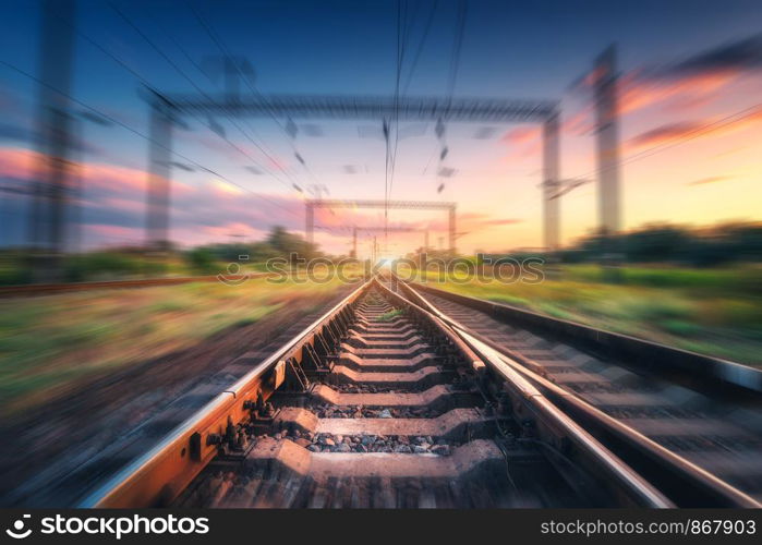 Railroad and colorful blue sky with clouds at sunset with motion blur effect in summer. Industrial landscape with railway station and blurred background. Railway platform in speed motion. Concept