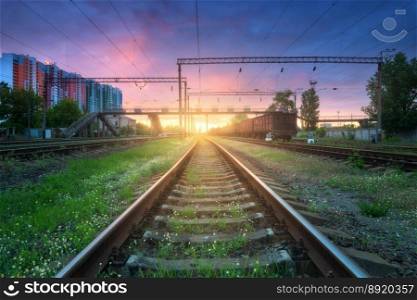 Railroad at sunset in summer. Beautiful industrial landscape with railway station, green grass, trees, buildings, colorful sky with clouds in spring. Railway platform in Ukraine. Transportation	