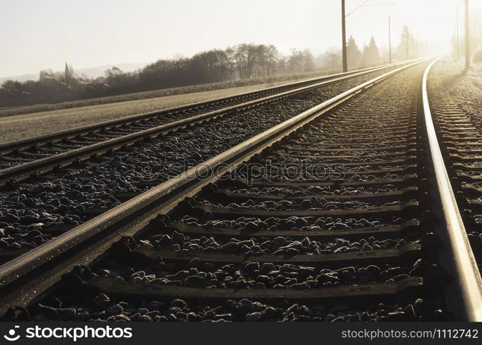 Railroad tracks at golden hour. Dutch angle perspective of rail tracks leading towards the sun. Way forward concept. German railway infrastructure.