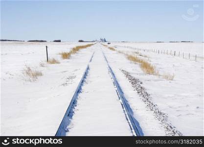 Railroad tracks in snow covered rural landscape.