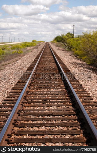 Railroad tracks lead off into the distance under a beautiful Teaxs Sky