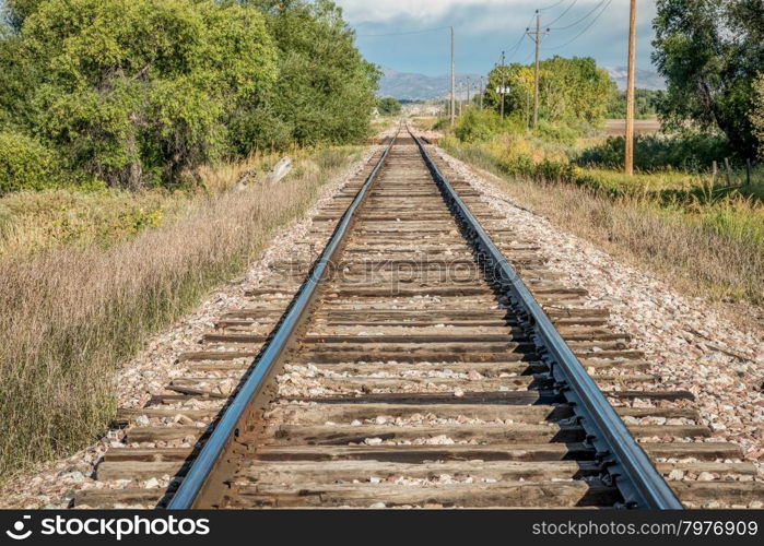 railroad tracks leading to distant foothills of Rocky Mountains in northern Colorado