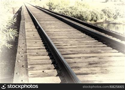 railroad tracks on a trestle crossing a river - travel concept, retro hand tinted opalotype processing