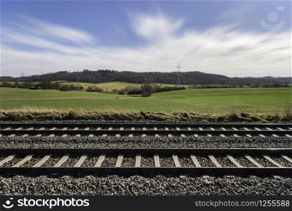 Railroad tracks through nature, on a sunny spring day. German railway infrastructure near Schwabisch Hall. Railroad lines and rural scene.