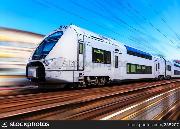 Railroad travel and railway tourism transportation industrial concept: scenic summer view of modern high speed passenger commuter train on tracks with motion blur effect