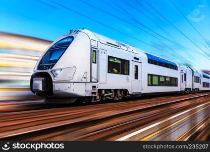 Railroad travel and railway tourism transportation industrial concept: scenic summer view of modern high speed passenger commuter train on tracks with motion blur effect