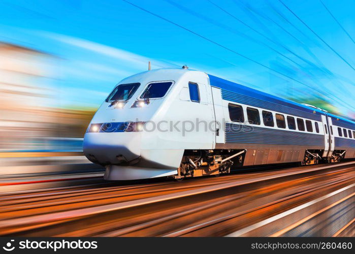 Railroad travel and railway tourism transportation industrial concept: scenic summer view of modern high speed passenger commuter train on tracks at the station platform with motion blur effect