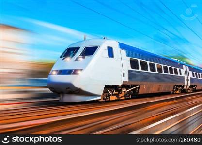 Railroad travel and railway tourism transportation industrial concept: scenic summer view of modern high speed passenger commuter train on tracks at the station platform with motion blur effect