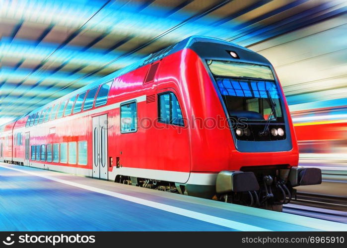 Railroad travel and railway tourism transportation industrial concept  scenic view of red modern high speed passenger commuter double decker train on tracks at the station platform with motion blur effect