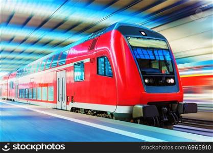 Railroad travel and railway tourism transportation industrial concept  scenic view of red modern high speed passenger commuter double decker train on tracks at the station platform with motion blur effect