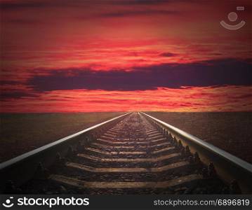 rails going away into the fiery red sunset. rails going away into the fiery red sunset. rails going away into the dark landscape with fiery red sunset