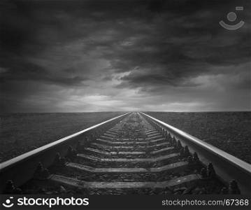 rails going away into the gloomy distance. rails going away into the gloomy distance. Black and white image with rails going away into the dark sky landscape