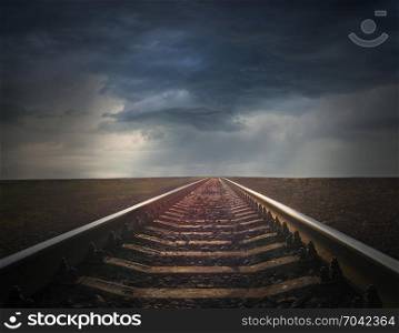 rails going away to the dark rainy clouds. rails going away to the dark rainy clouds. gloomy landscape. Black and white image with rails going away into the dark sky landscape