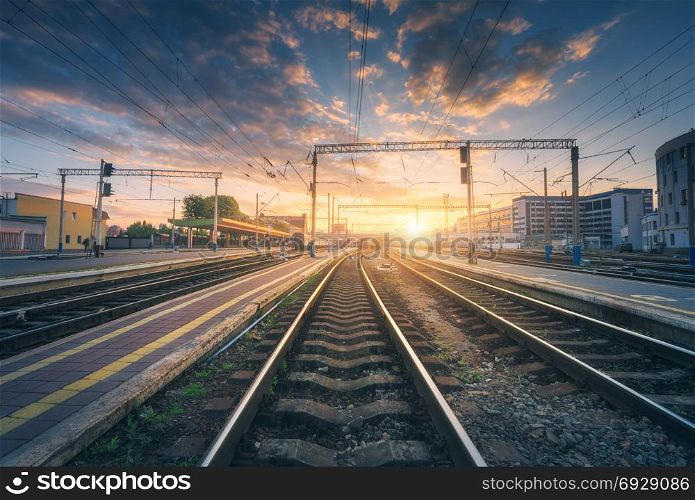 Railway station and beautiful colorful sky at sunset. Industrial landscape with railroad, blue sky with red and orange clouds in dusk. Railway junction in the evening. Railway platfform.Transportation
