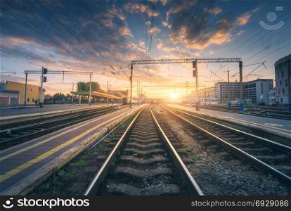 Railway station and beautiful colorful sky at sunset. Industrial landscape with railroad, blue sky with red and orange clouds in dusk. Railway junction in the evening. Railway platfform.Transportation