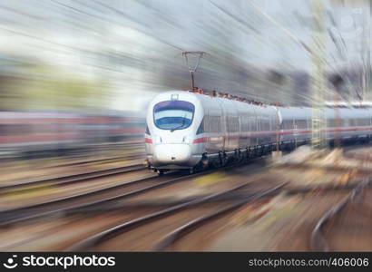 Railway station with modern high speed train in motion in the evening in Nuremberg, Germany. White train on the railroad track. Motion blur effect