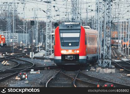 Railway station with modern red commuter train at sunset in Nuremberg, Germany. Railroad with vintage toning