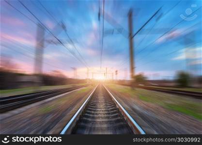 Railway station with motion blur effect at sunset. Blurred railroad. Industrial conceptual landscape with blurred railway station, blue sky with colorful clouds and sunlight. Railway track.Background. Railway station with motion blur effect. Blurred railroad. Railway station with motion blur effect. Blurred railroad