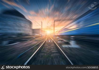 Railway station with motion blur effect. Blurred railroad. Industrial conceptual landscape with blurred railway station, speed train, blue sky with colorful clouds and sun. Railway track. Background. Railway station with motion blur effect. Blurred railroad