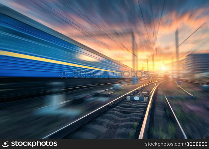 Railway station with motion blur effect. Blurred railroad. Industrial conceptual landscape with blurred railway station, speed train, blue sky with colorful clouds and sun. Railway track. Background. Railway station with motion blur effect. Blurred railroad