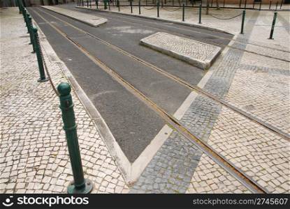 railway tracks on typical portuguese calcada stone pavement at the sidewalk