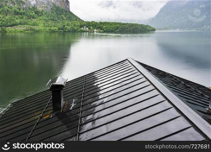 Rain and clouds on the Hallstattersee in Austria. Morning mist over the Austrian landscape with lake, forests, fields, pastures, meadows and wet roofs.