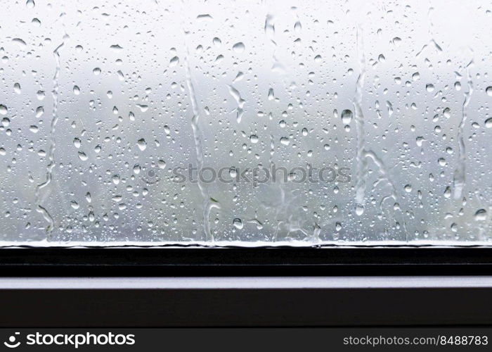rain drops and trickles of rain closeup on window in heavy rain