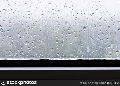 rain drops and trickles of rain closeup on window in heavy rain